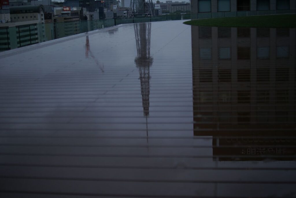 雨に濡れた中日ビルのウッドデッキとテレビ塔の反射