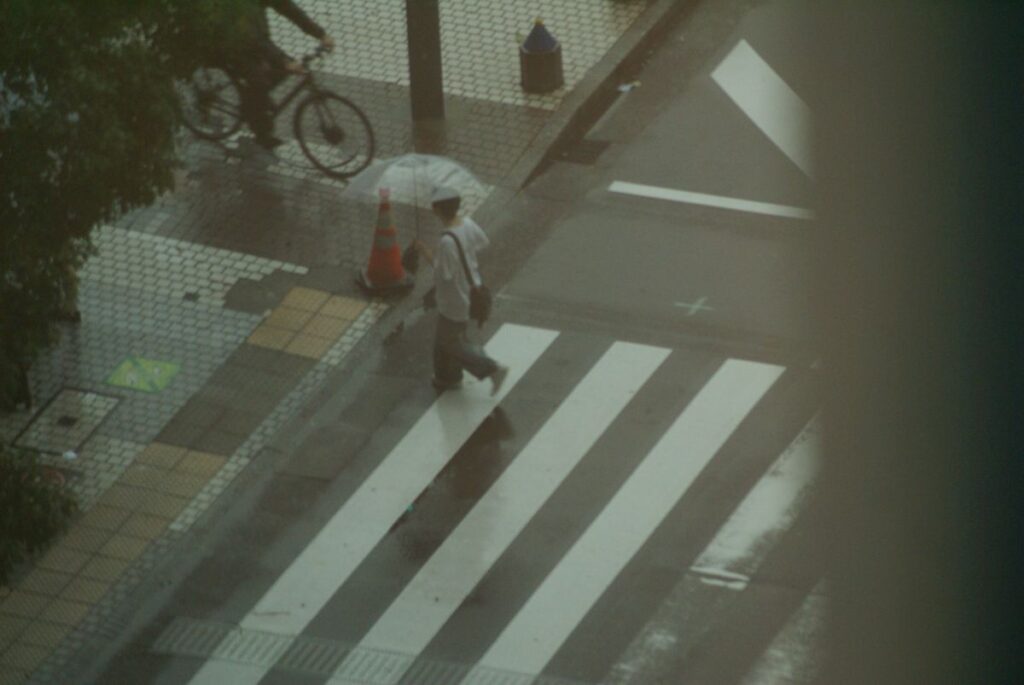 望遠レンズの圧縮効果で捉えた雨の日の横断歩道と傘を差す人々