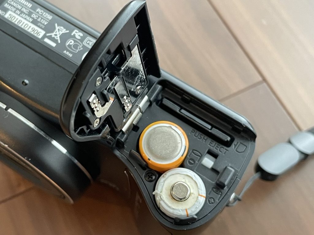 PowerShot SX100 ISの底面バッテリー室を開いた状態。出先でも入手しやすい単3電池2本で駆動する実用的な仕様。